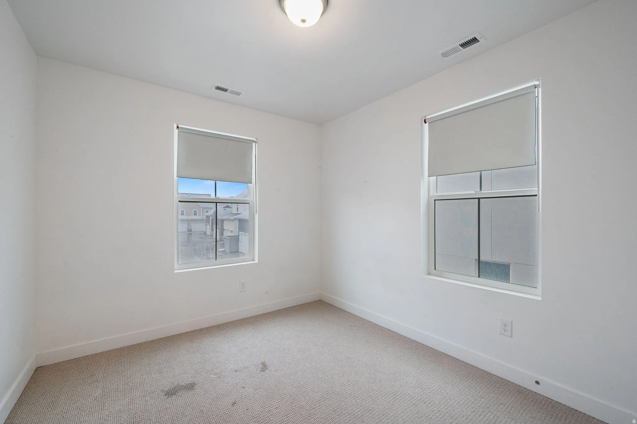 Empty room with light colored carpet and baseboards