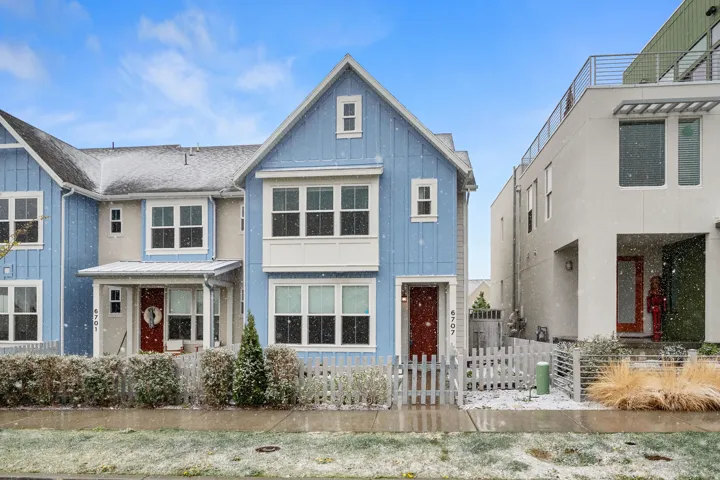 View of front facade with board and batten siding, a fenced front yard, a gate, and a standing seam roof