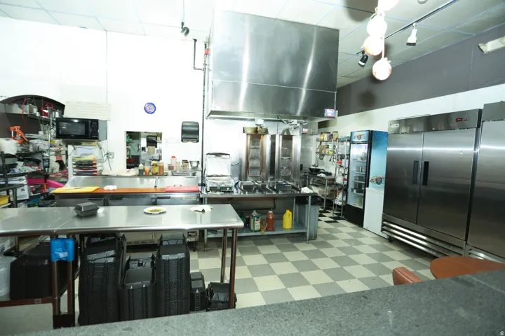 Kitchen featuring high end refrigerator, stainless steel fridge, open shelves, black microwave, and a paneled ceiling