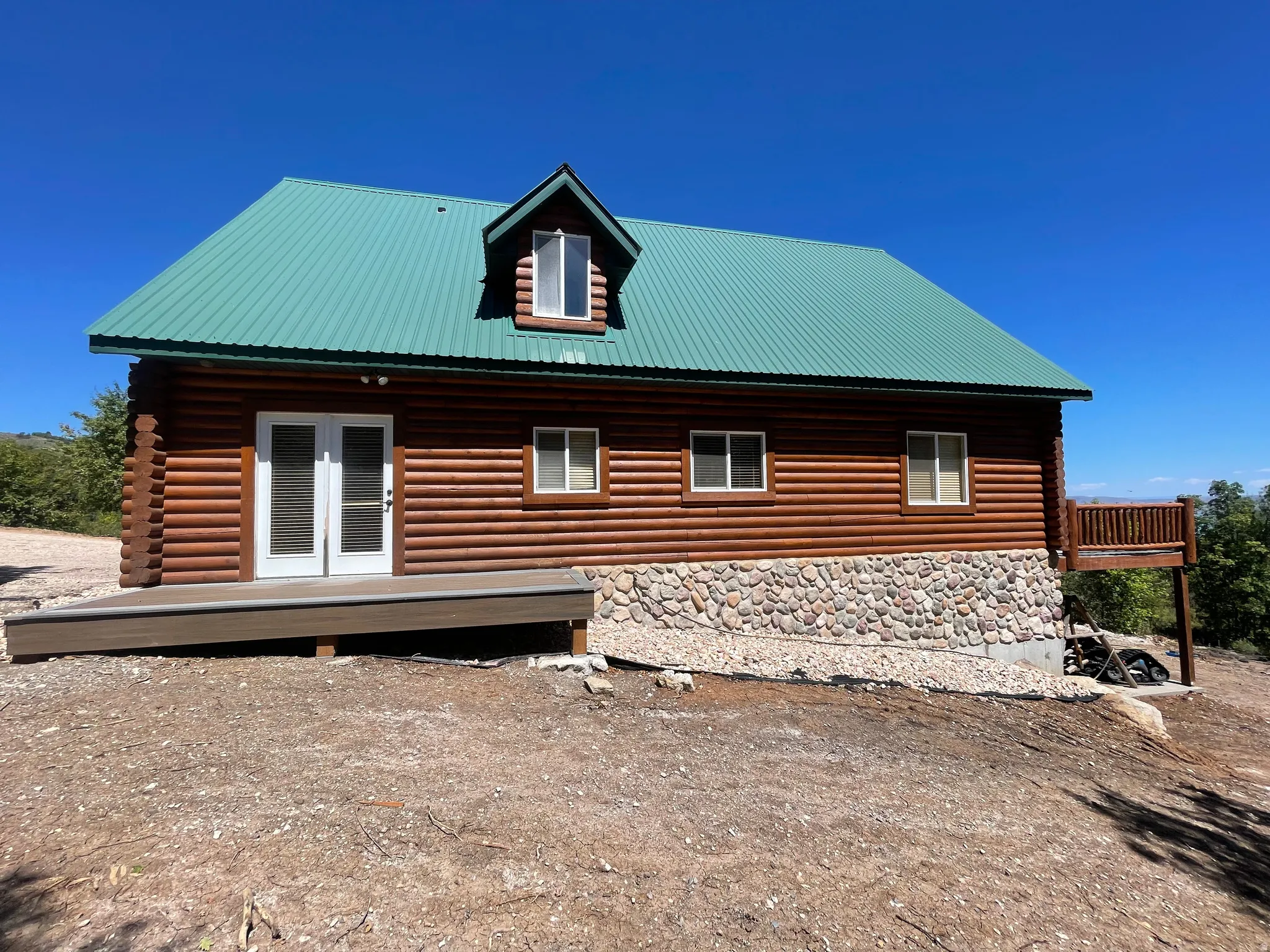 View of side of home featuring a metal roof, a deck, french doors, and stone siding