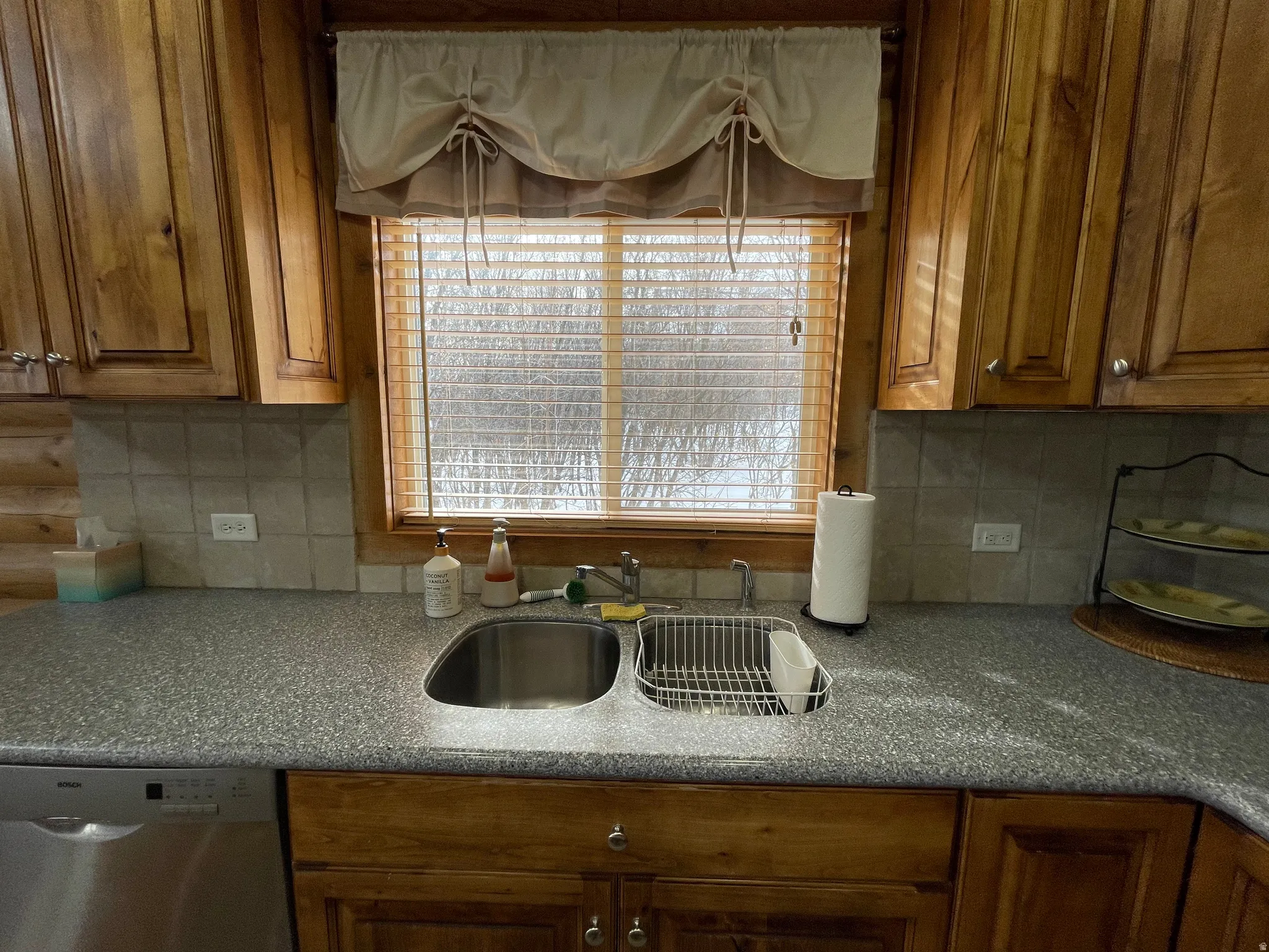 Kitchen featuring dishwasher, wood finish cabinets, and decorative backsplash