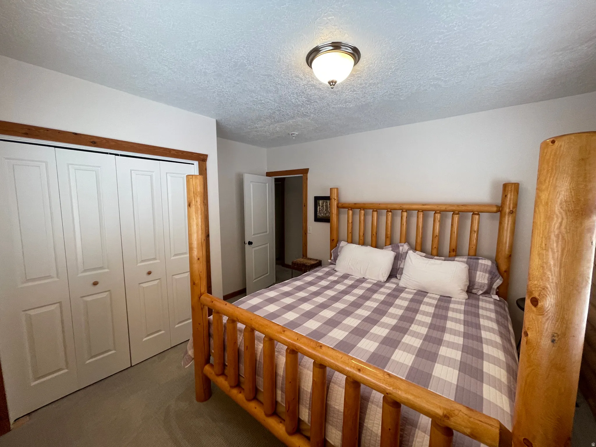 Bedroom with a textured ceiling, a closet, and dark colored carpet
