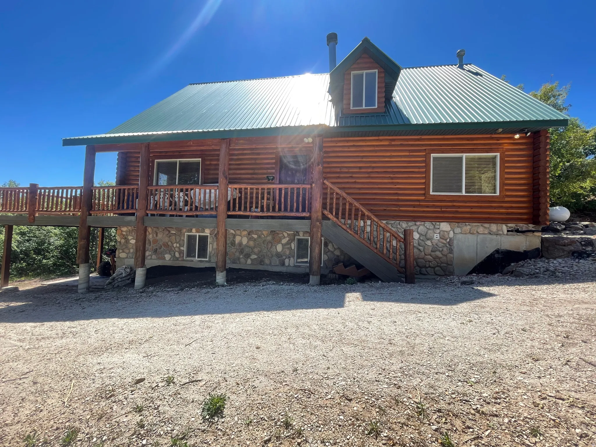 Rear view of house with a metal roof, a porch, and stone siding