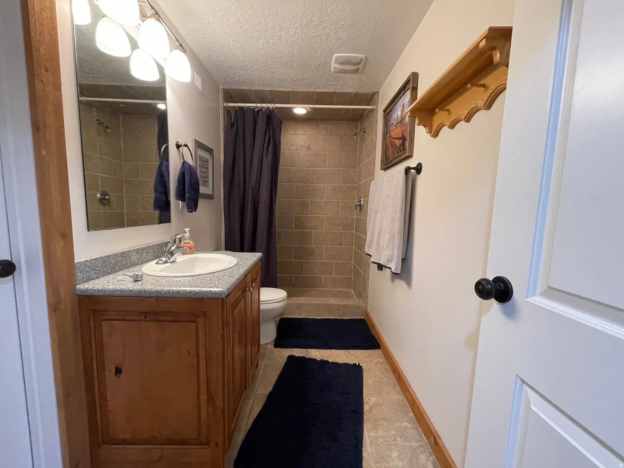 Bathroom featuring a textured ceiling, vanity, a stall shower, and light tile patterned floors