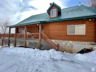 Snow covered rear of property featuring a metal roof and a porch