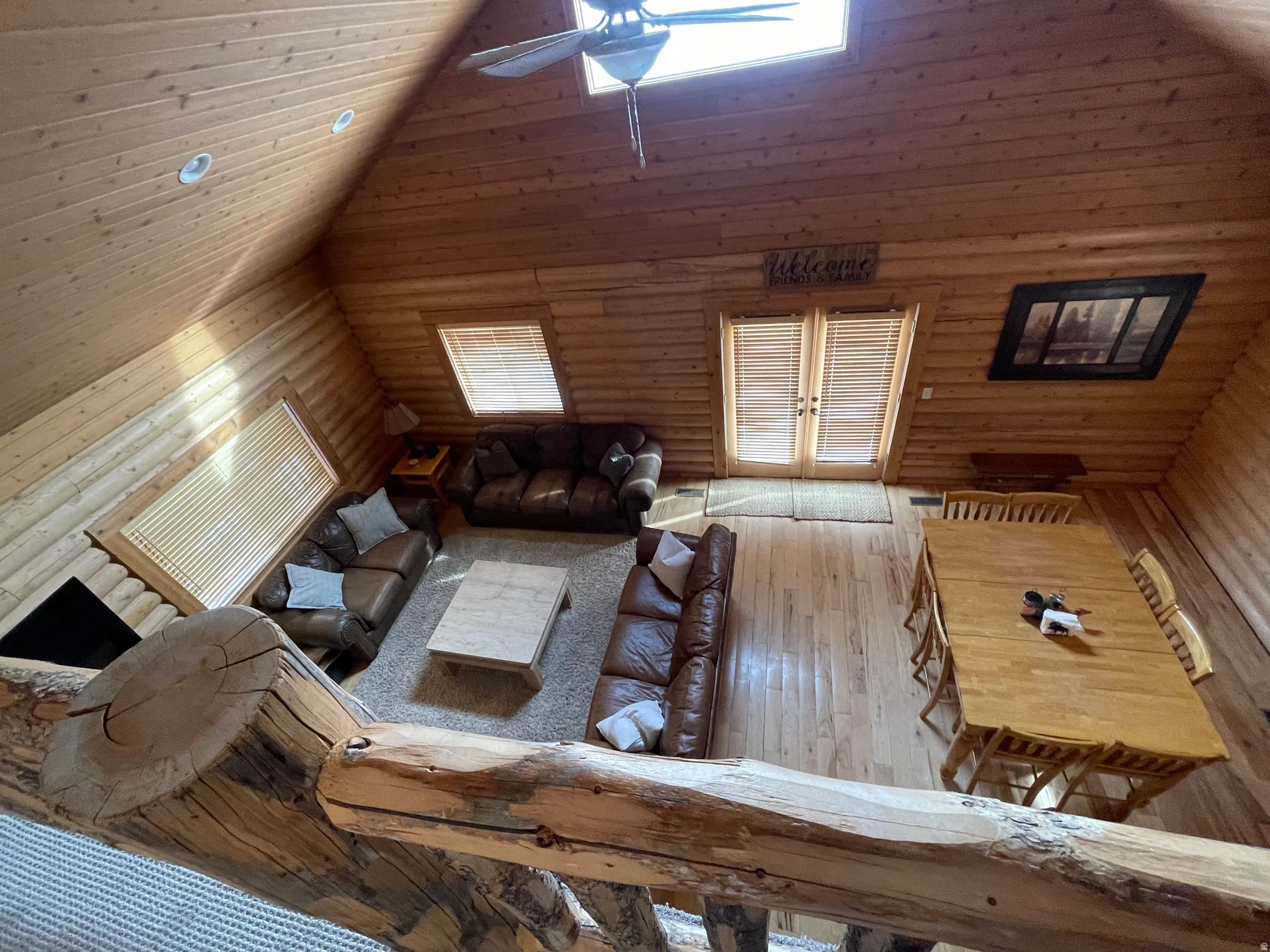 Living room with wood-type flooring, ceiling fan, and a vaulted wooden ceiling