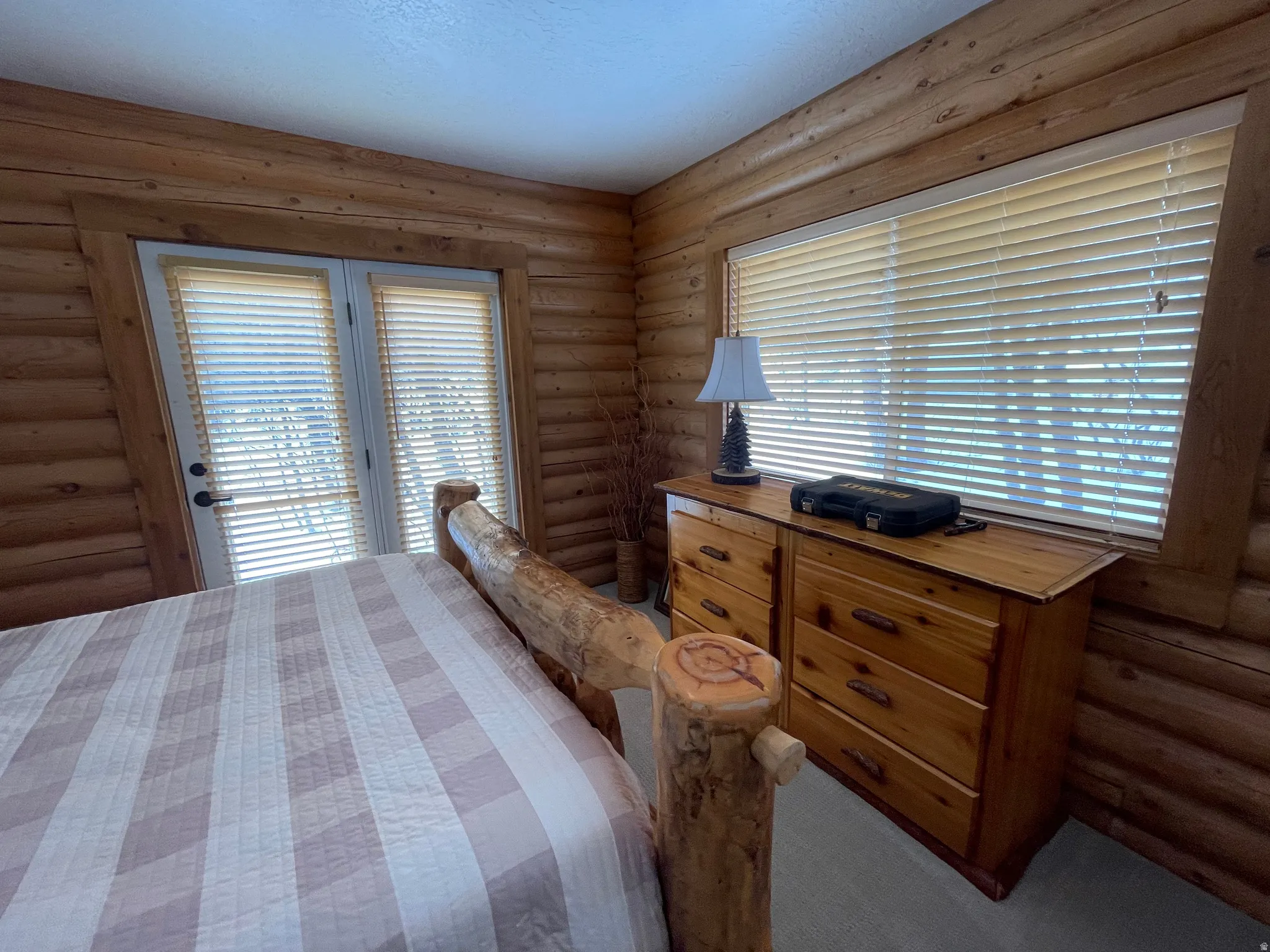 Bedroom with log walls, access to exterior, and dark colored carpet