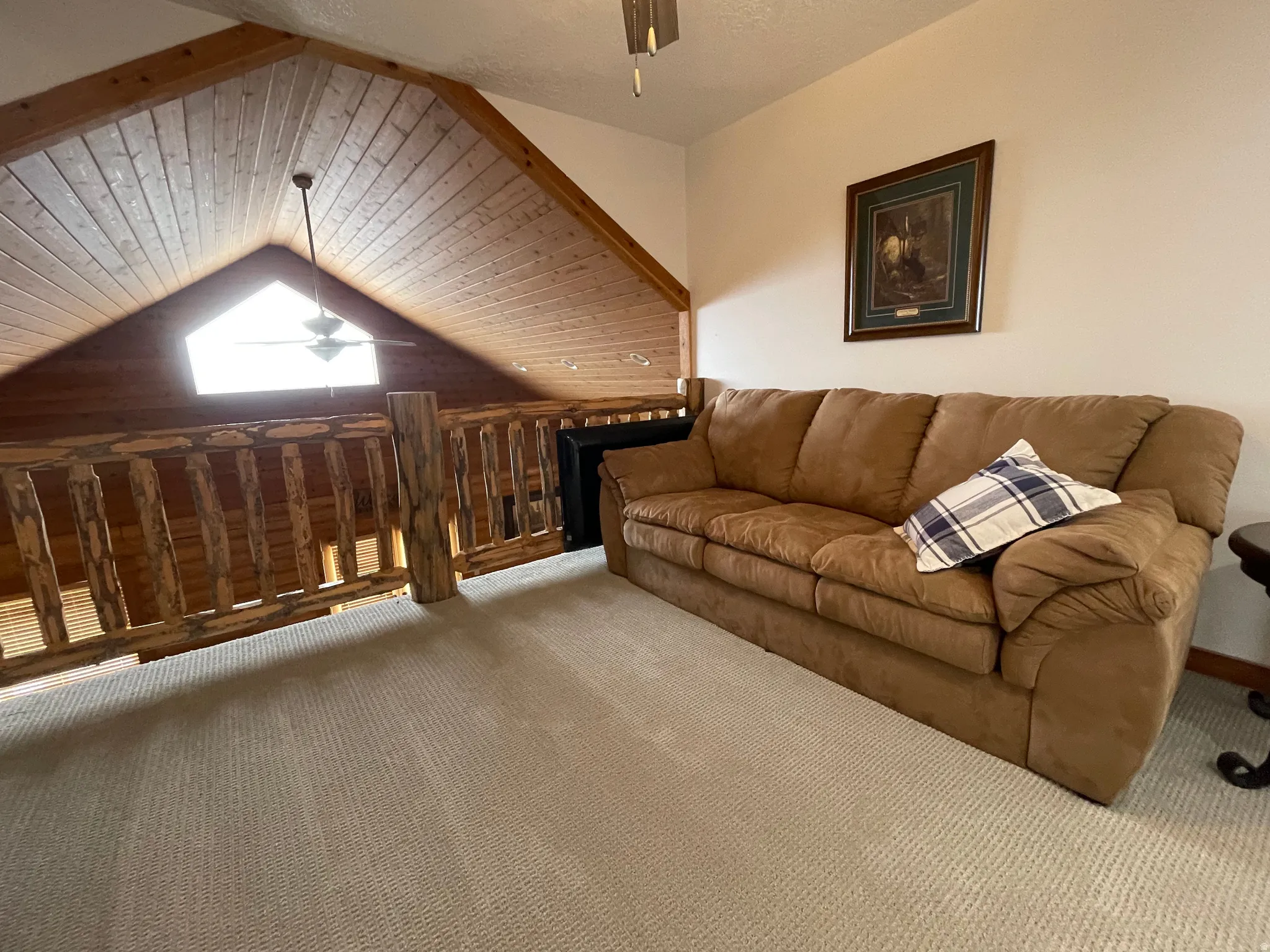 Carpeted living area with a ceiling fan and wood ceiling