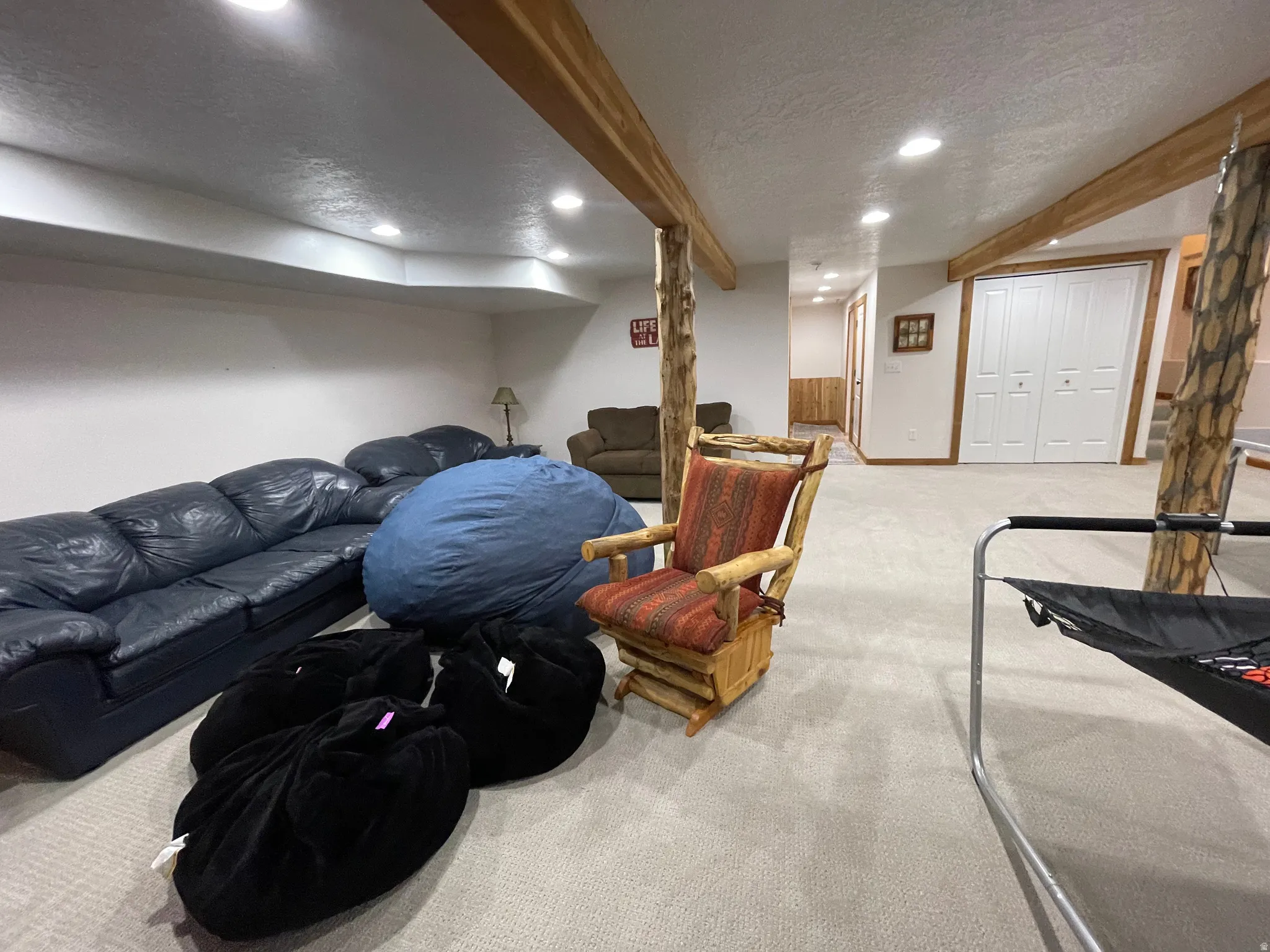 Living room featuring light colored carpet, a textured ceiling, beam ceiling, and recessed lighting