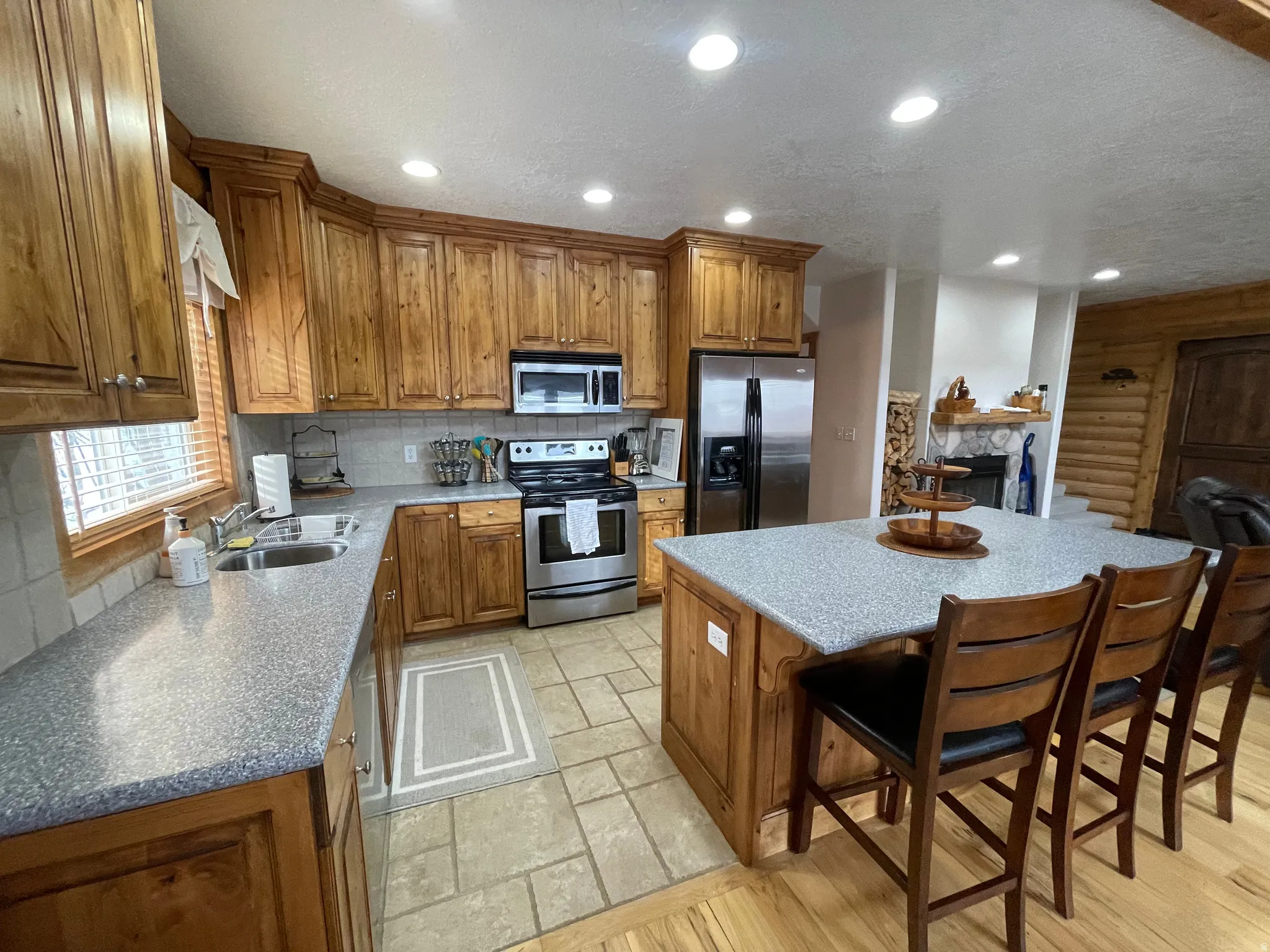 Kitchen featuring wood finish cabinets, stainless steel appliances, a breakfast bar area, a kitchen island, and backsplash