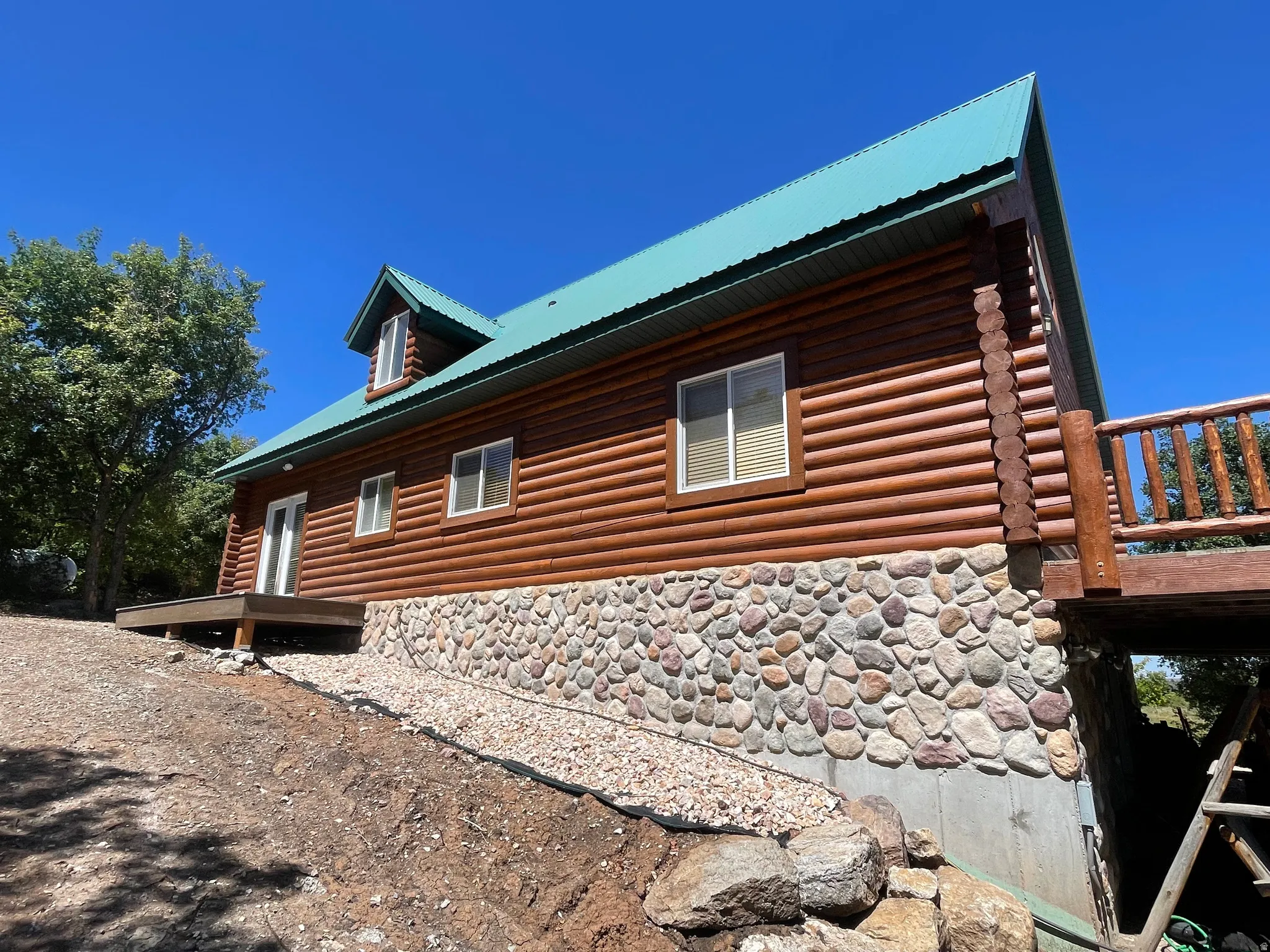 View of side of property with a metal roof and stone siding