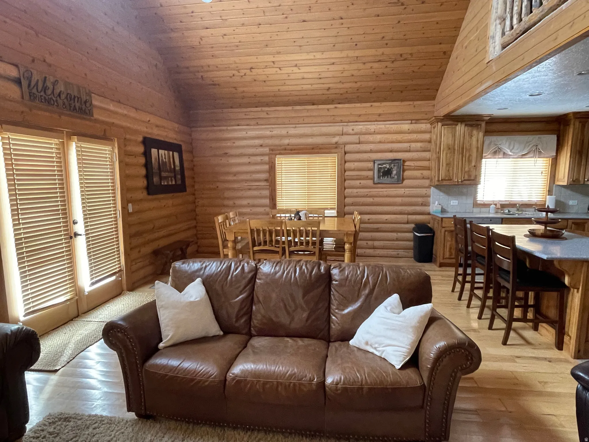 Living room with log walls, a vaulted wood ceiling, and light wood finished floors