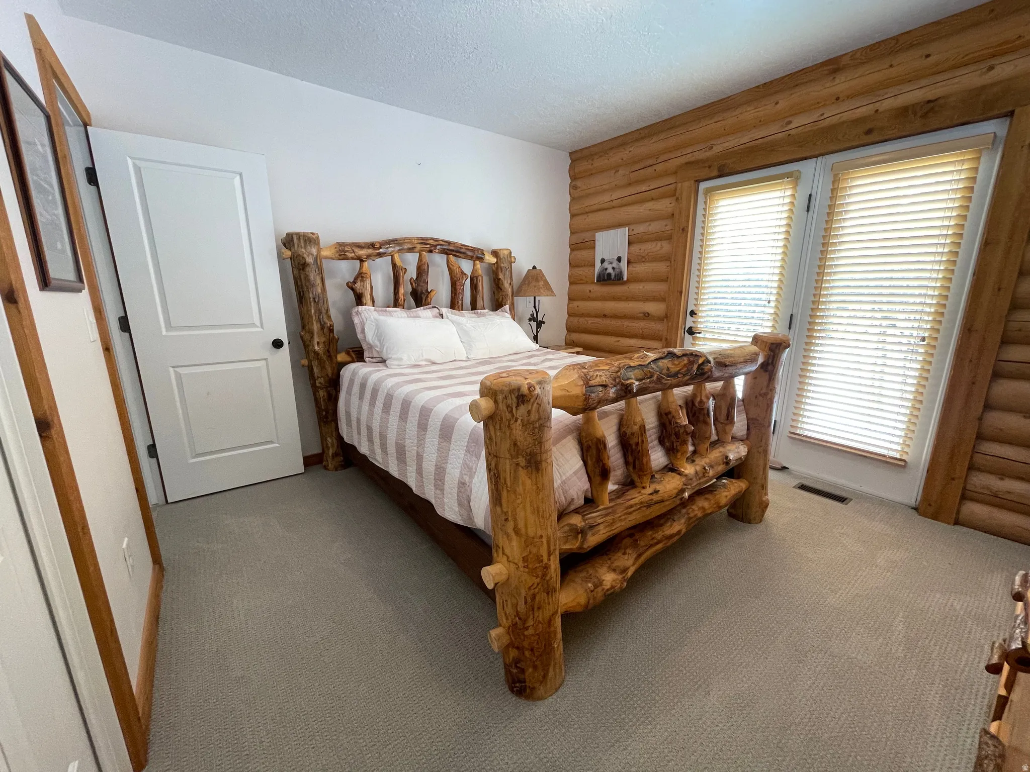 Bedroom featuring rustic walls, a textured ceiling, and carpet