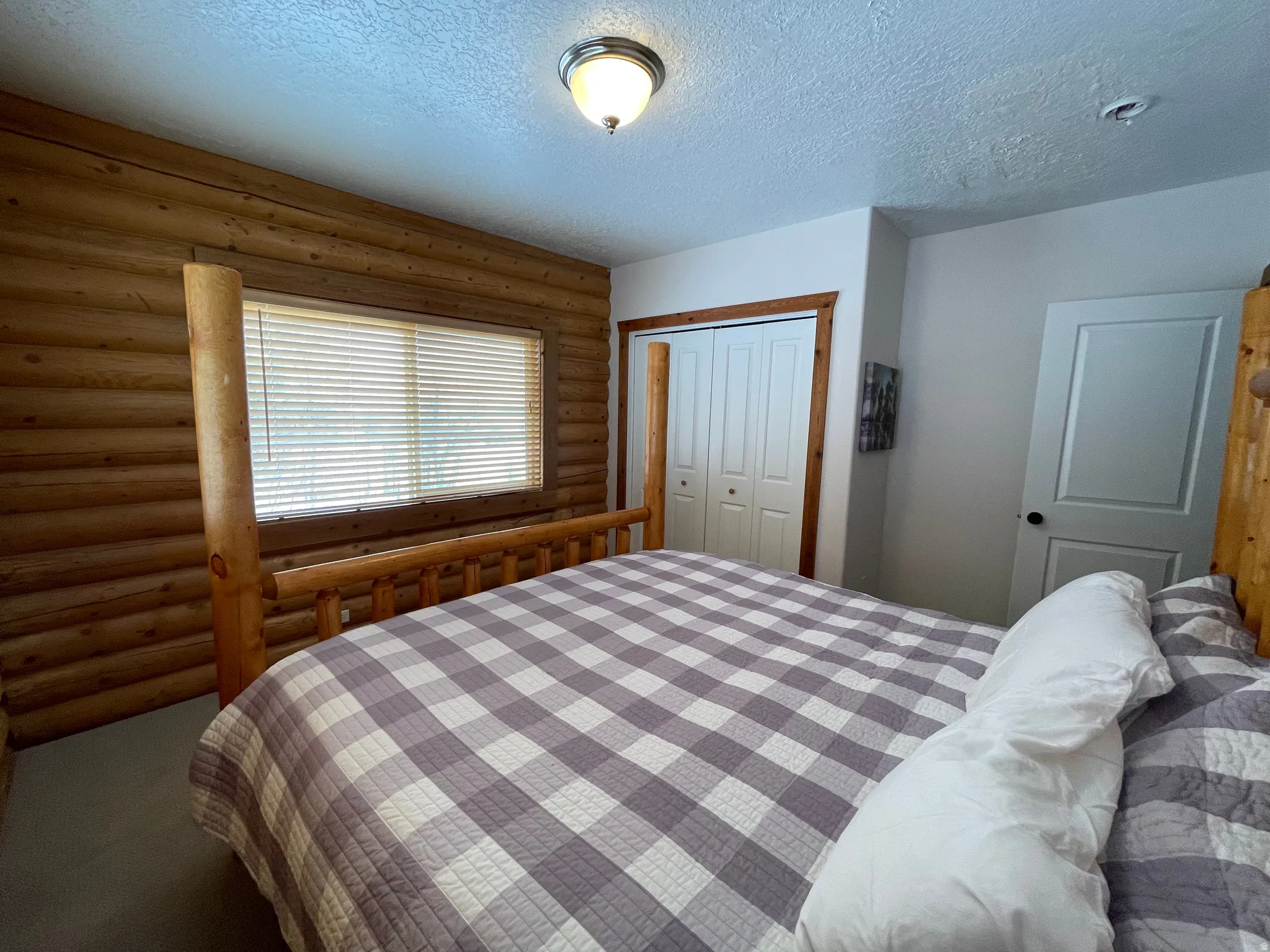 Carpeted bedroom with rustic walls, a closet, and a textured ceiling