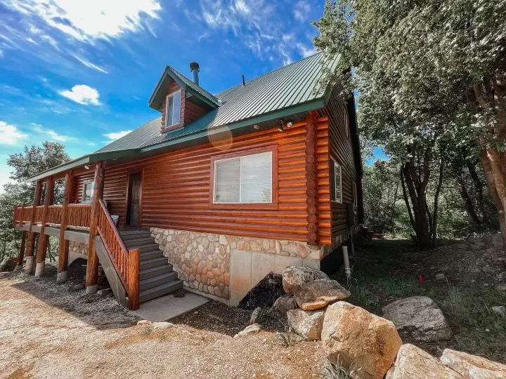 View of side of home with a metal roof, log exterior, and stone siding