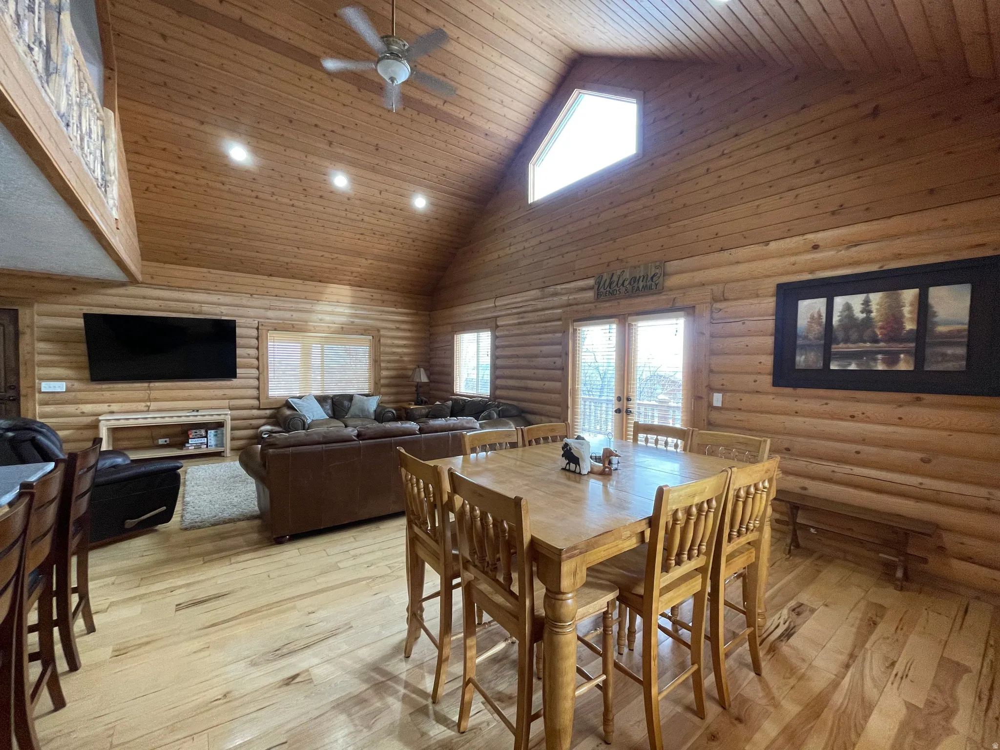 Dining space with rustic walls, french doors, a high wooden ceiling, ceiling fan, and plenty of natural light