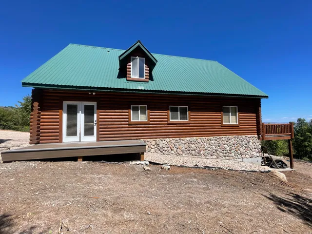 View of side of home featuring a metal roof, a deck, french doors, and stone siding
