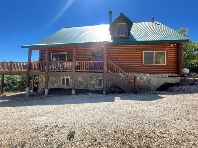 Rear view of house with a metal roof, a porch, and stone siding