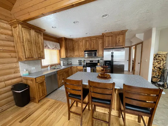 Kitchen featuring decorative backsplash, wood finish cabinets, stainless steel appliances, a breakfast bar area, and light wood-style floors
