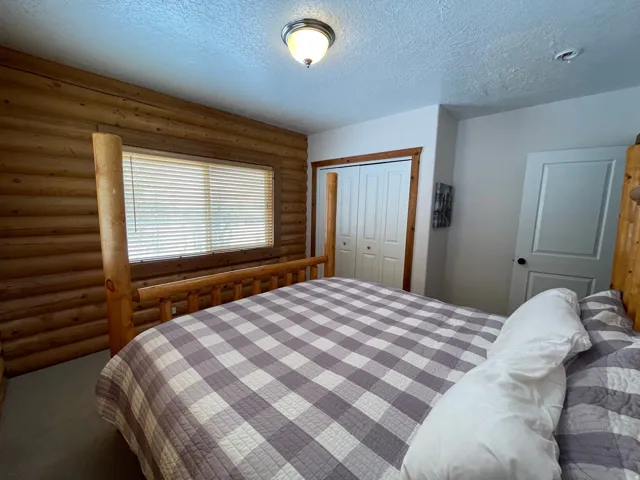 Carpeted bedroom with rustic walls, a closet, and a textured ceiling