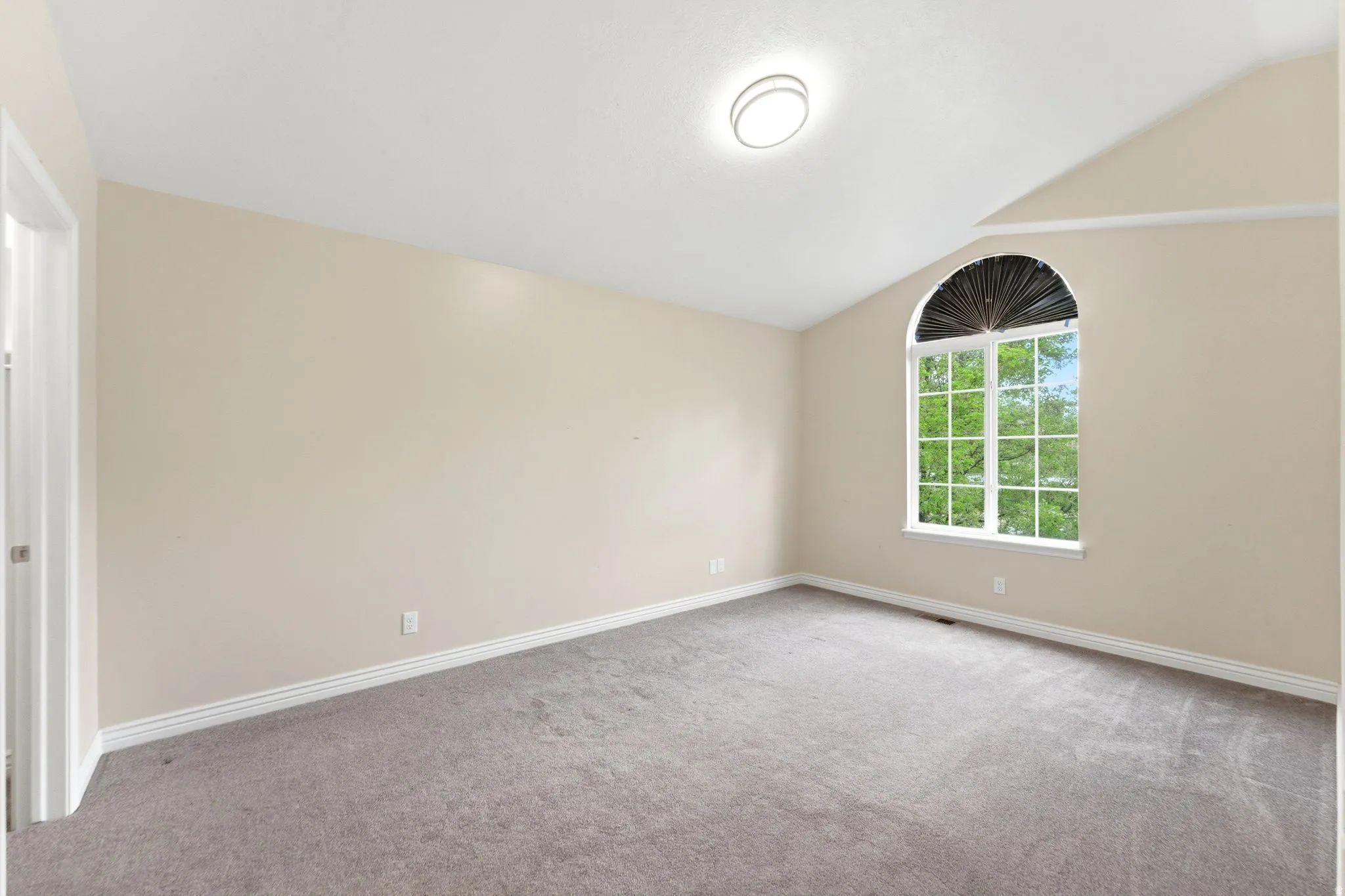 Spare room featuring vaulted ceiling and light carpet