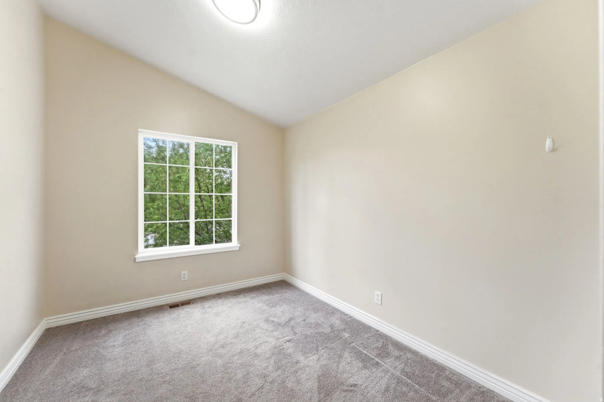 Spare room featuring vaulted ceiling and light carpet