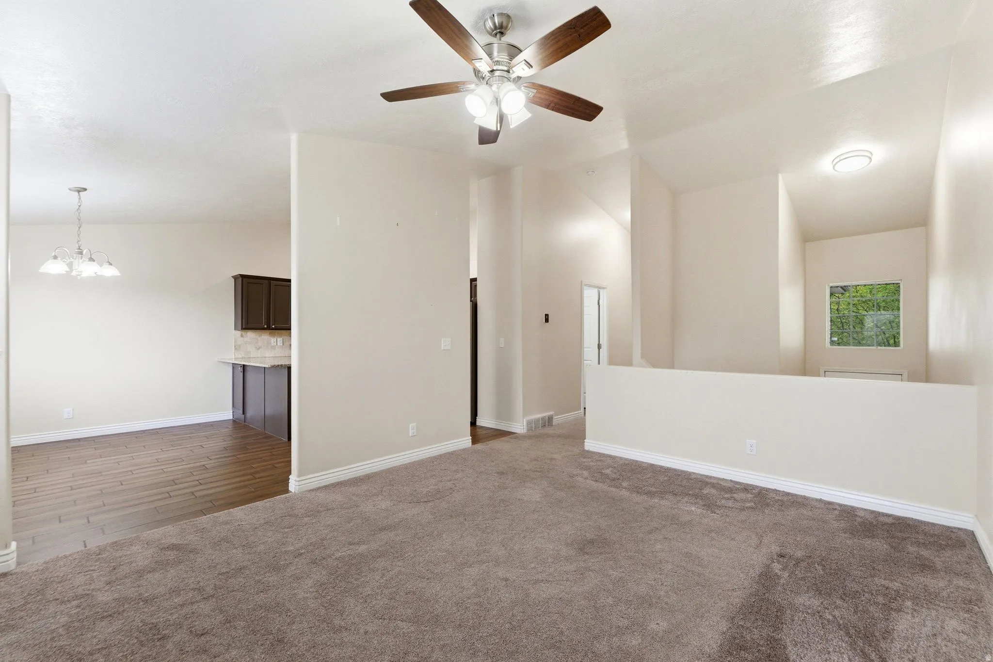 Spare room featuring dark colored carpet, suspended lighting, and a ceiling fan