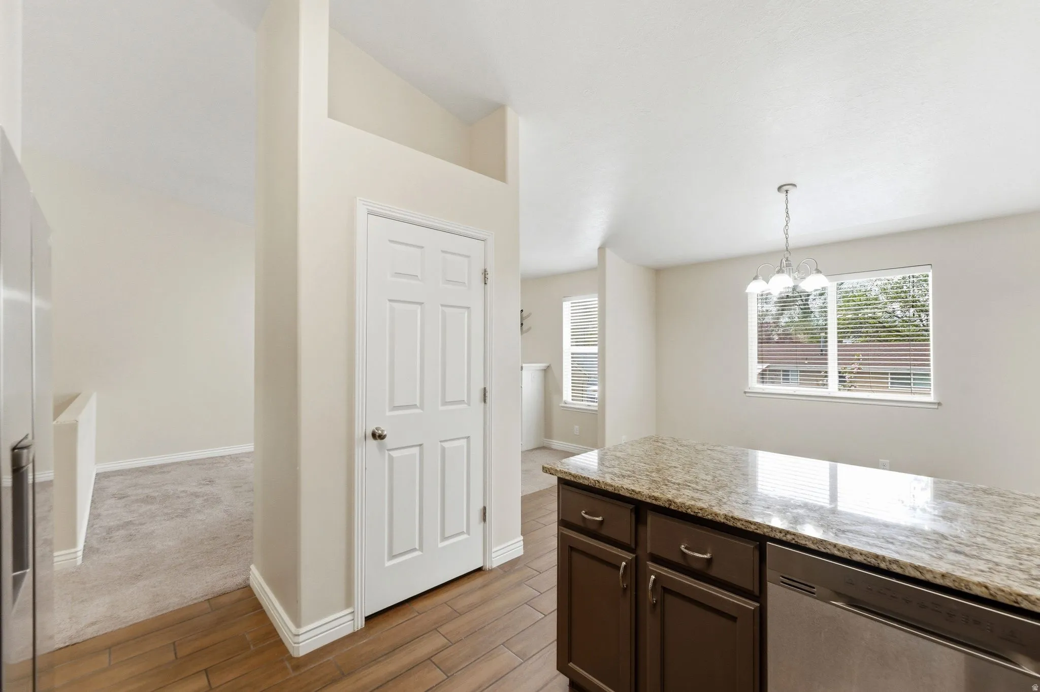 Kitchen with light stone counters, stainless steel appliances, wood finish floors, a chandelier, and dark wood finish cabinets