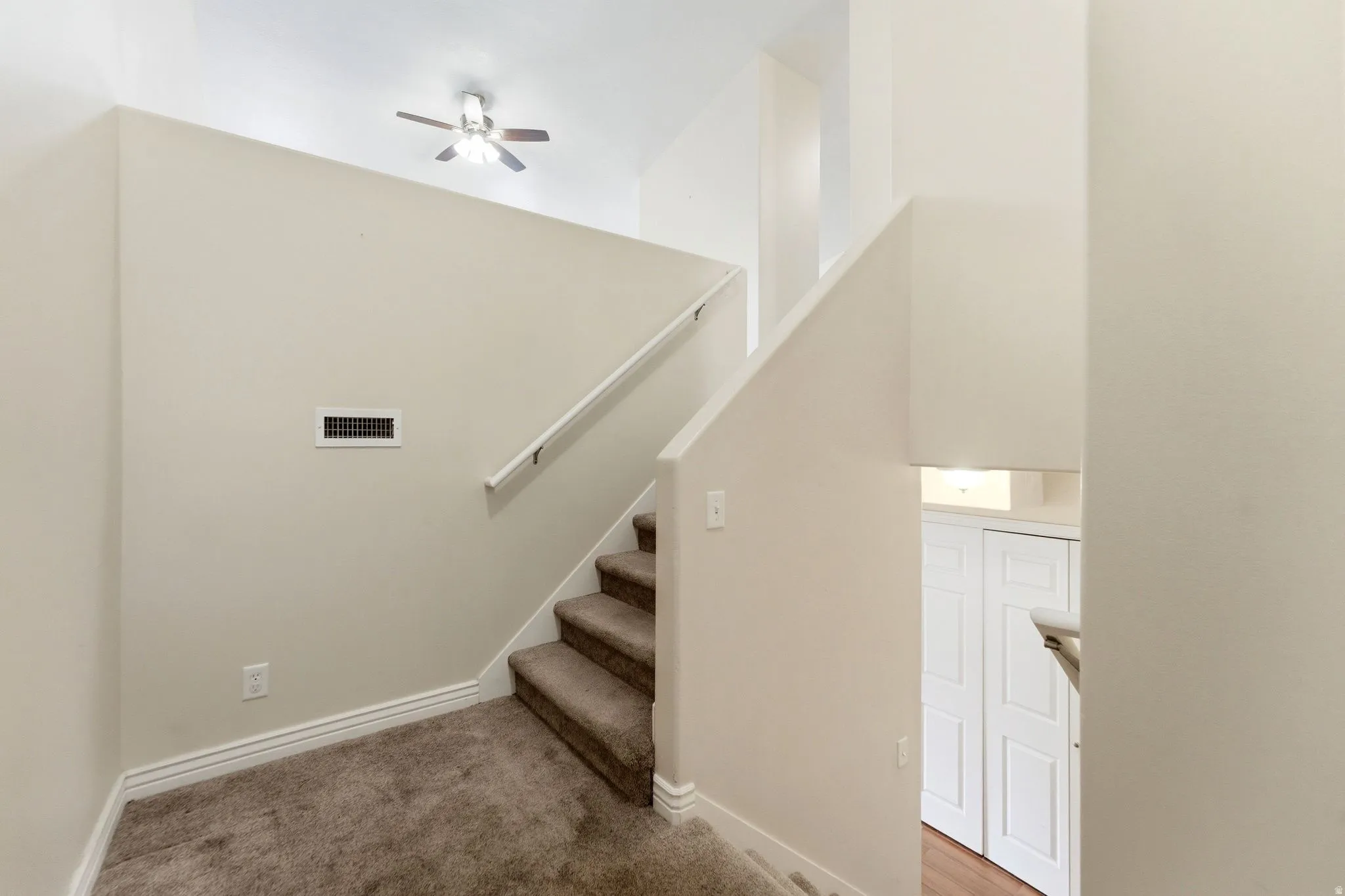 Staircase featuring carpet floors and ceiling fan