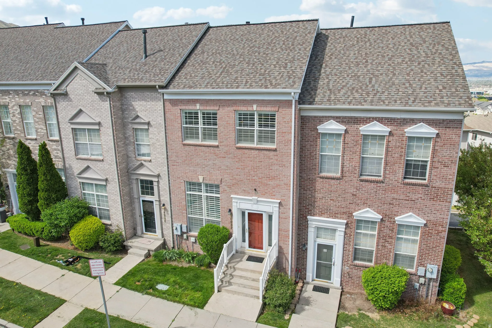 Colonial-style house featuring a shingled roof and brick siding