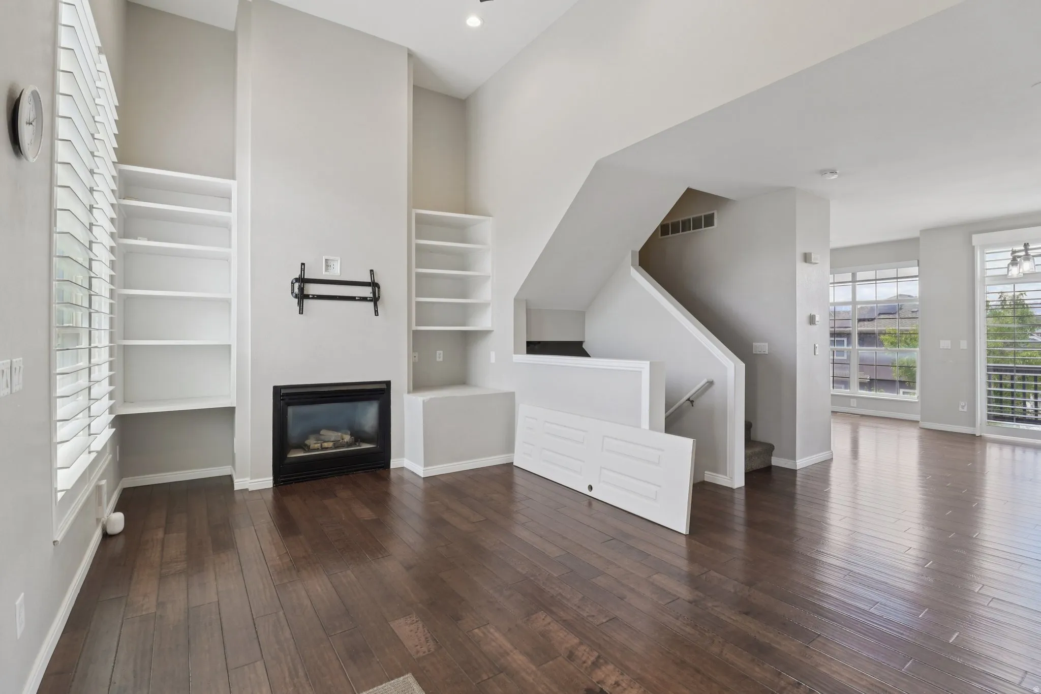 Unfurnished living room featuring dark wood-style flooring and a glass covered fireplace