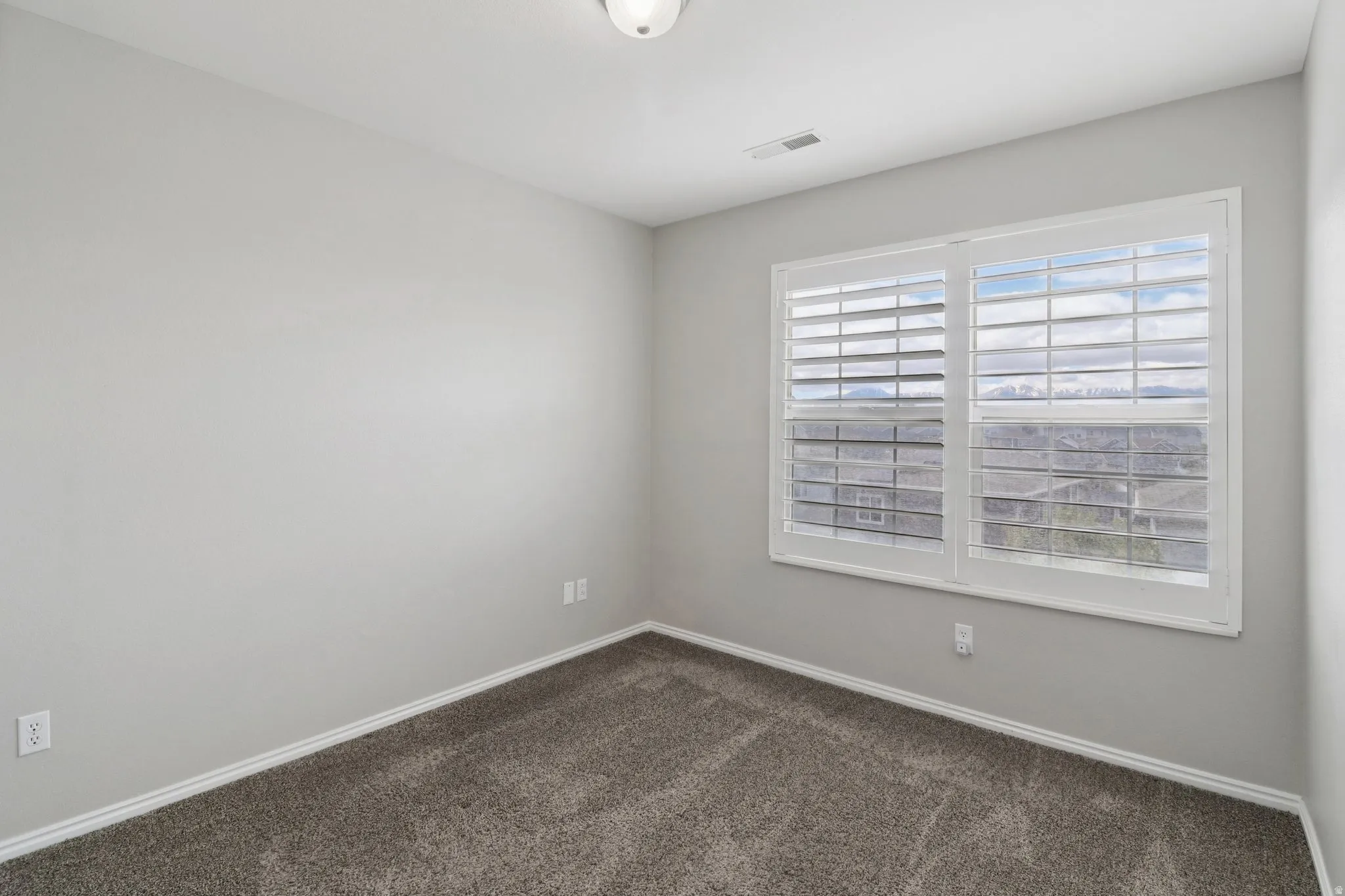 Empty room with dark carpet and baseboards