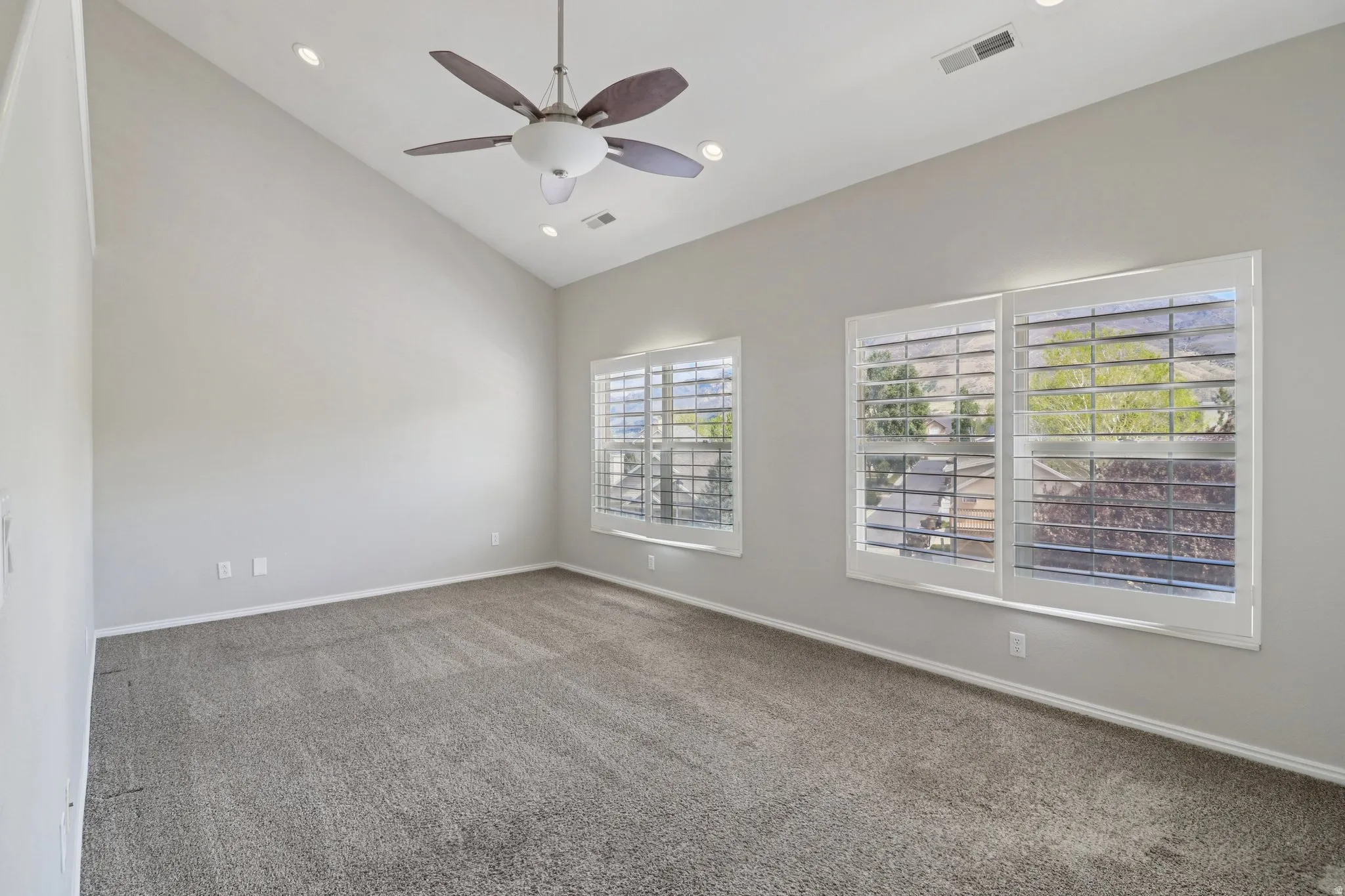Carpeted spare room with lofted ceiling, a ceiling fan, and recessed lighting