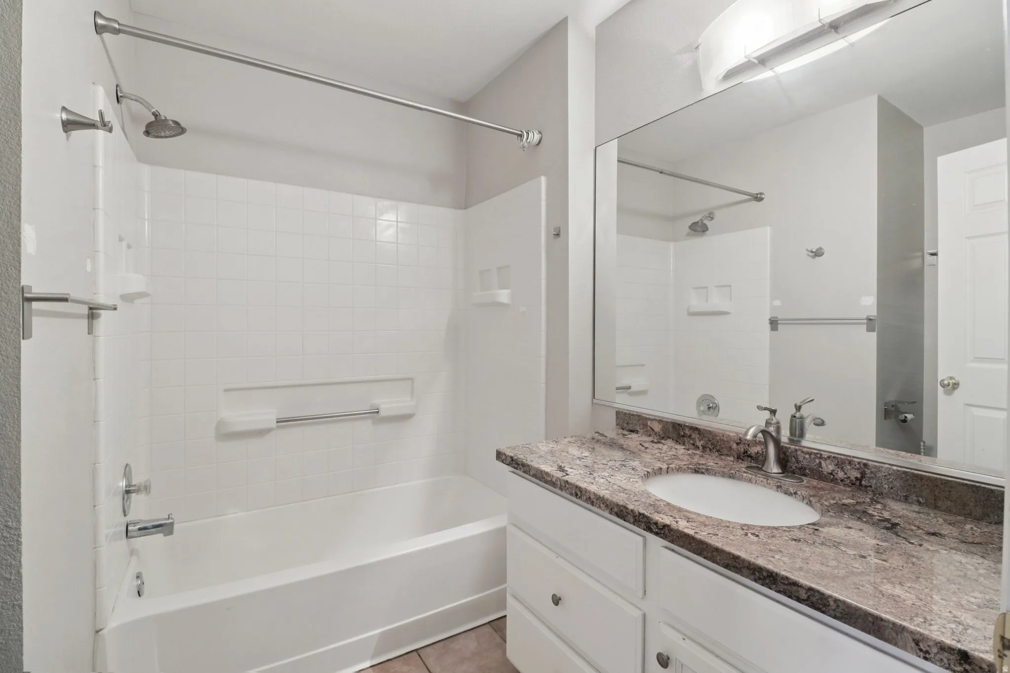 Bathroom featuring vanity, washtub / shower combination, and light tile patterned floors