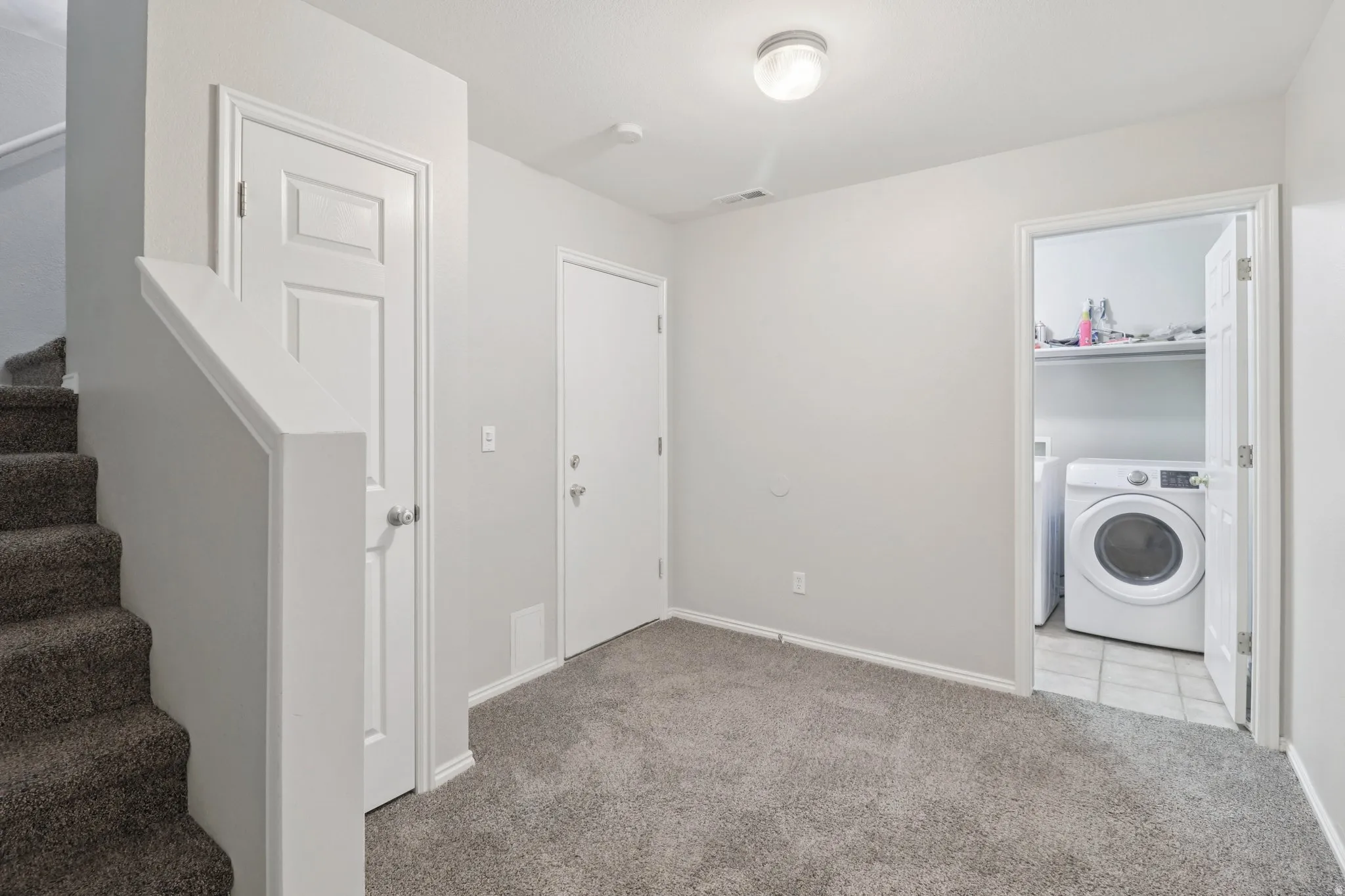 Laundry room featuring washer / clothes dryer and light carpet