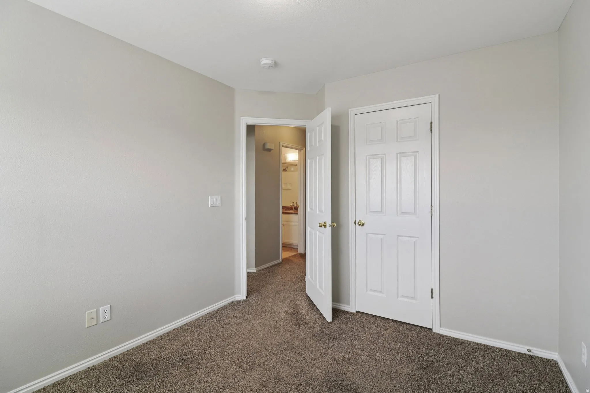 Unfurnished bedroom with dark colored carpet and baseboards