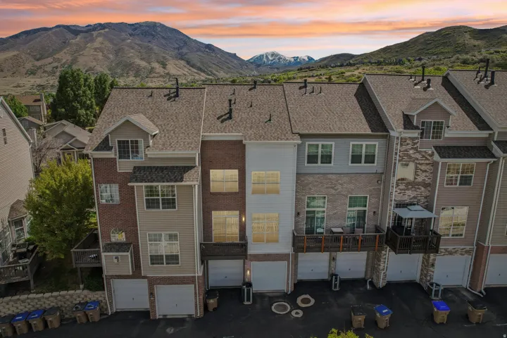 Back of property at dusk with a mountain view, an attached garage, brick siding, and driveway