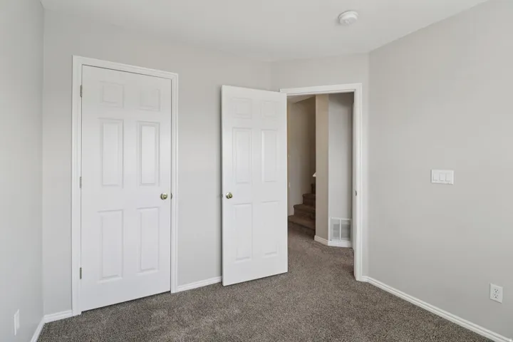 Unfurnished bedroom featuring dark colored carpet and baseboards