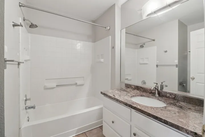 Bathroom featuring vanity, washtub / shower combination, and light tile patterned floors