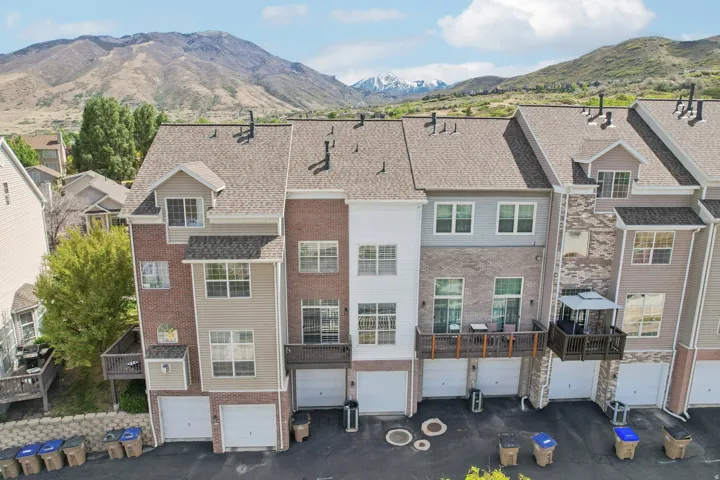 Back of house featuring a mountain view, brick siding, a garage, and driveway