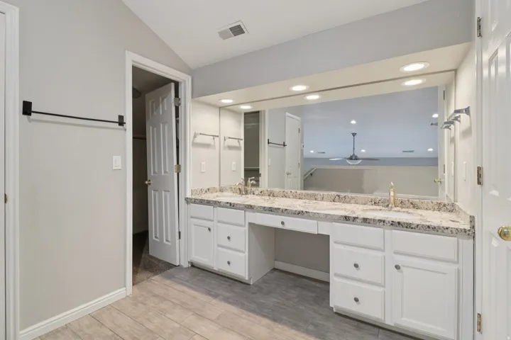 Bathroom with double vanity, light wood-style floors, lofted ceiling, and recessed lighting