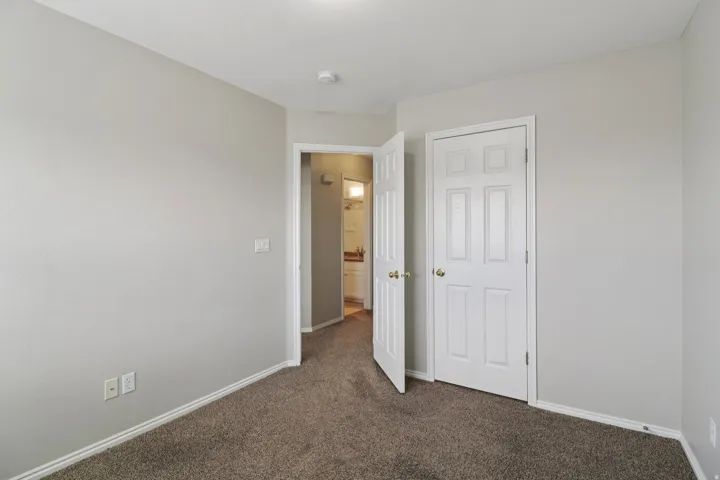 Unfurnished bedroom with dark colored carpet and baseboards