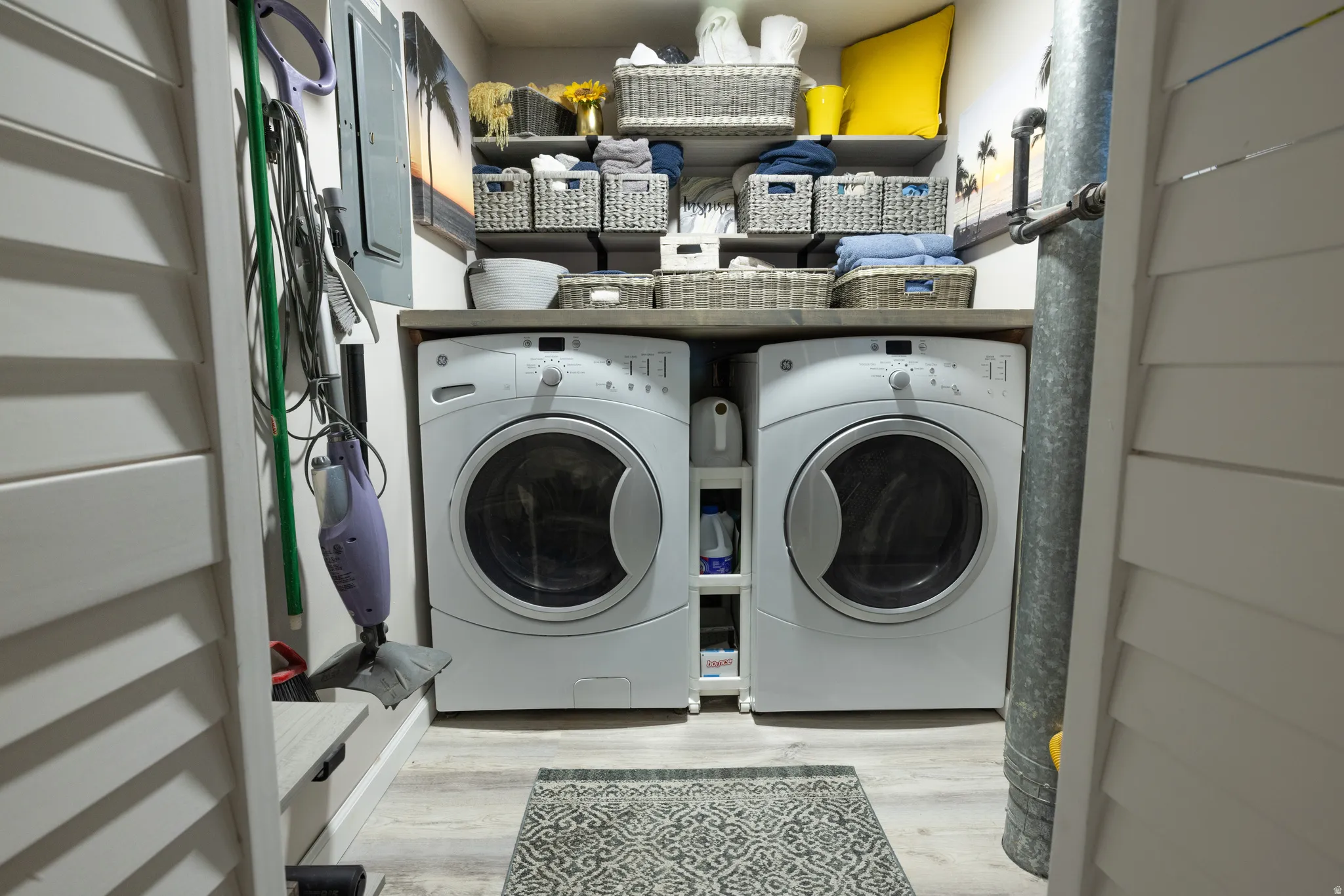Laundry room with light wood-type flooring, separate washer and dryer, and electric panel