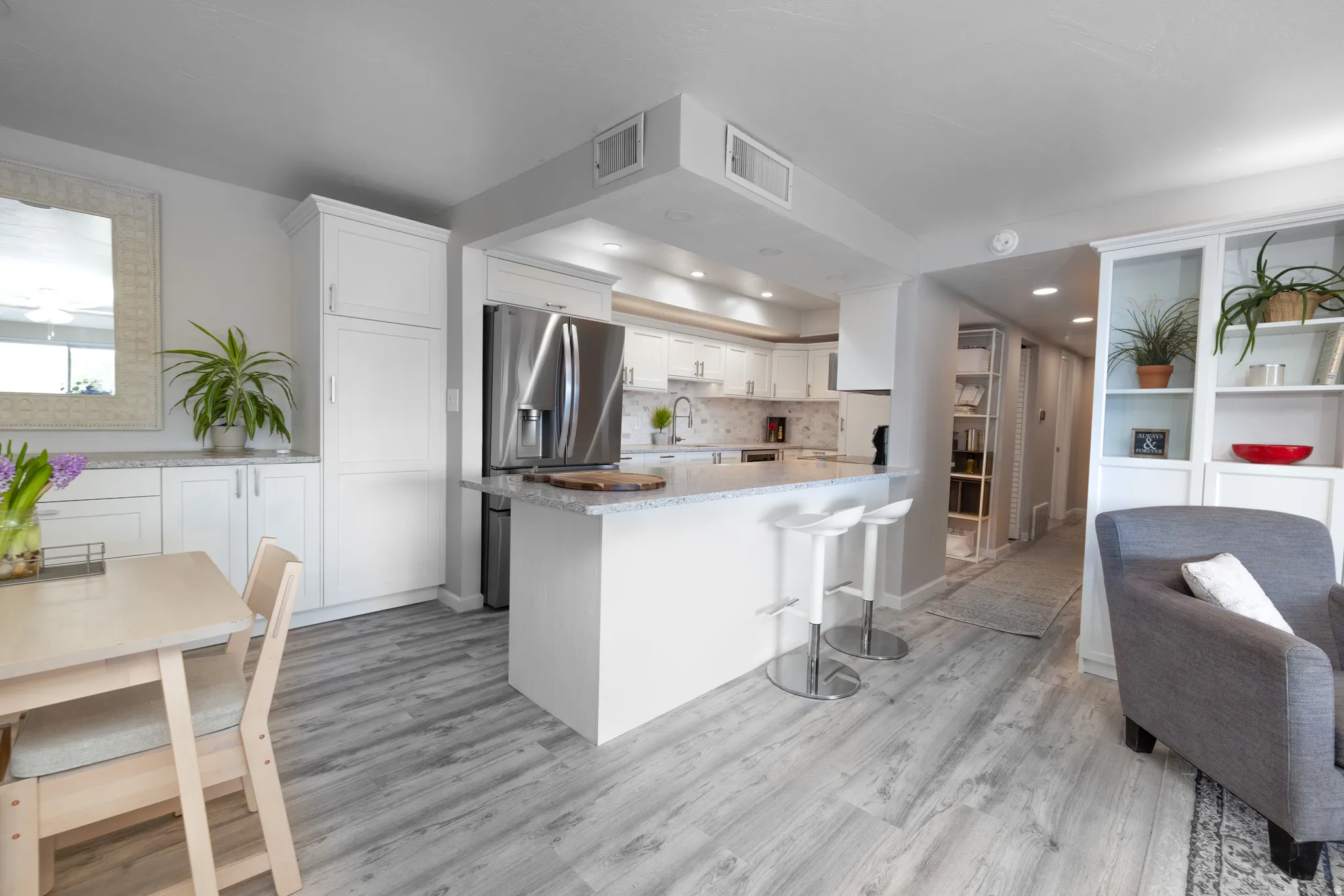 Kitchen with light stone counters, white cabinets, a breakfast bar area, light wood finished floors, and backsplash