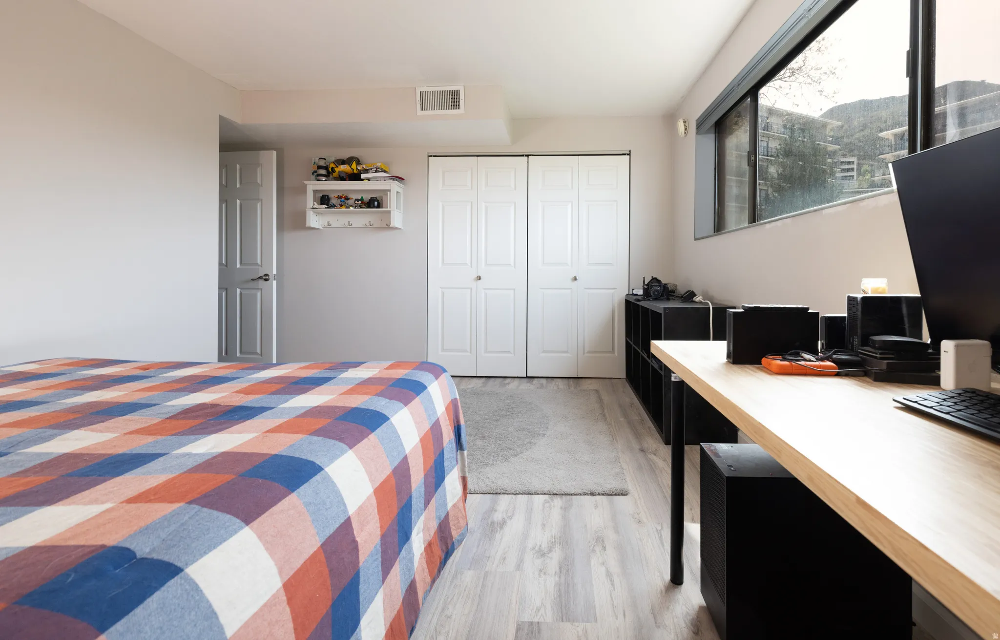 Bedroom featuring light wood-style floors, a closet, and a desk
