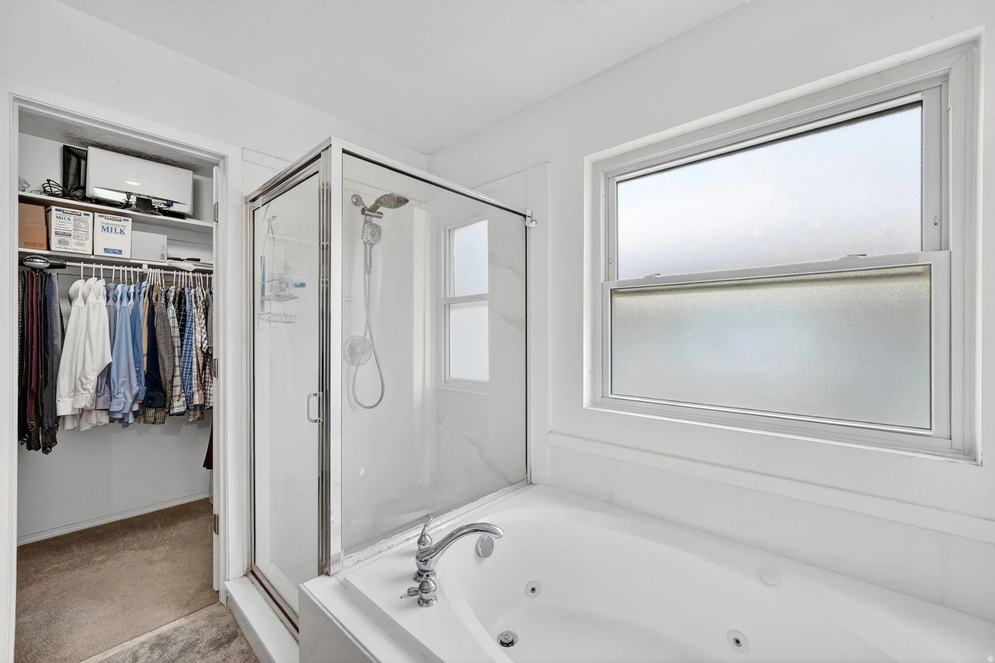 Bathroom featuring a spacious closet, a shower stall, and a tub with jets