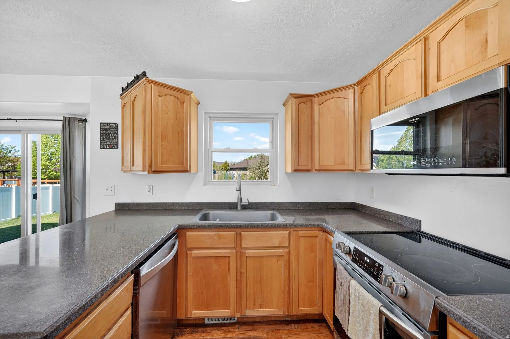 Kitchen with stainless steel appliances, a textured ceiling, and wood finished floors