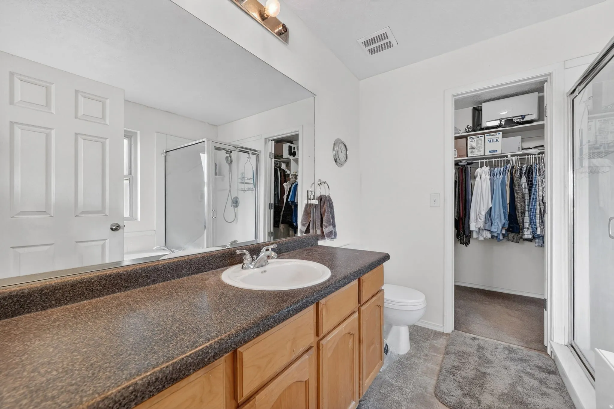Bathroom with a walk in closet, a stall shower, and vanity