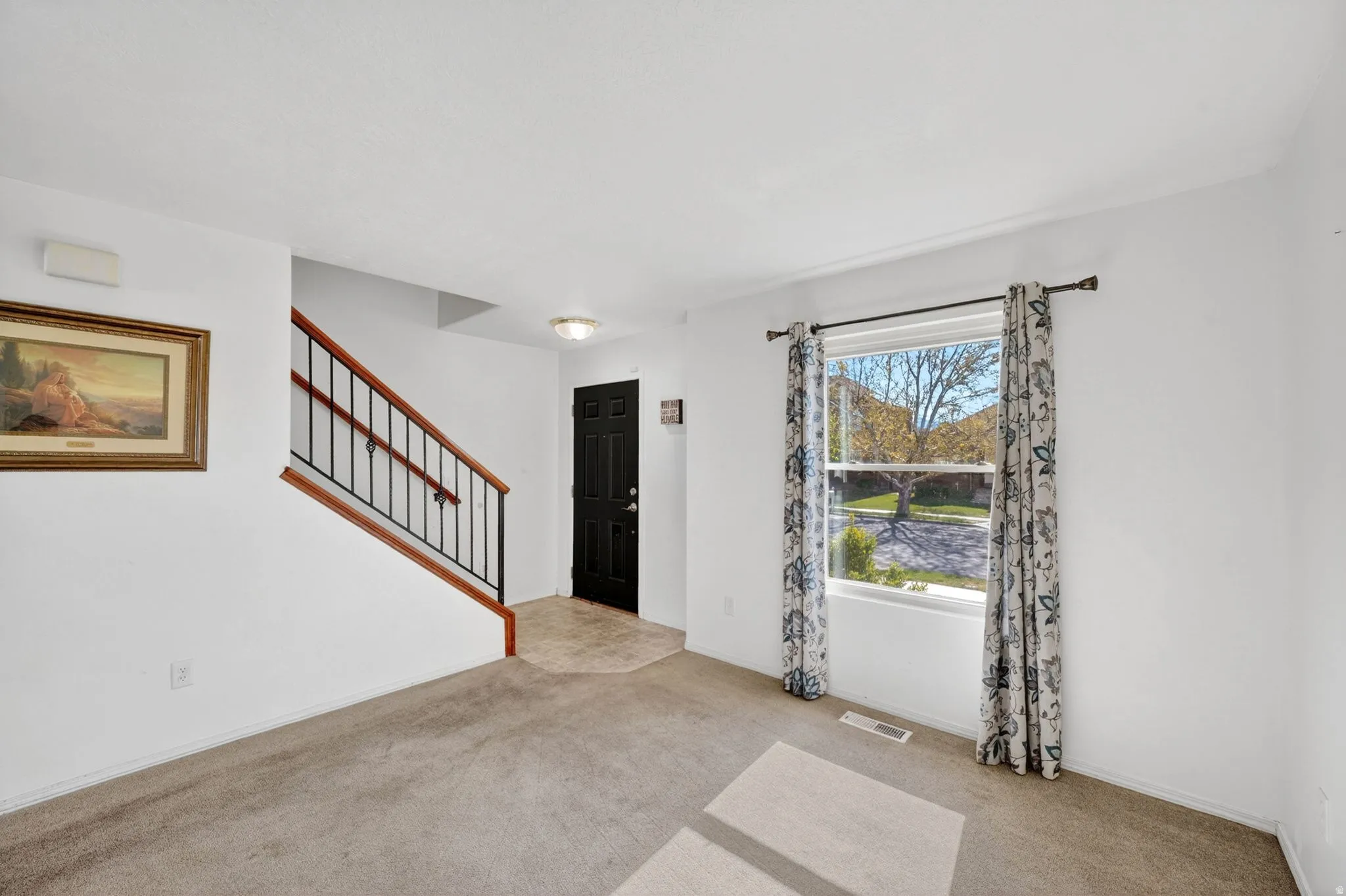 Foyer entrance featuring stairway and light colored carpet