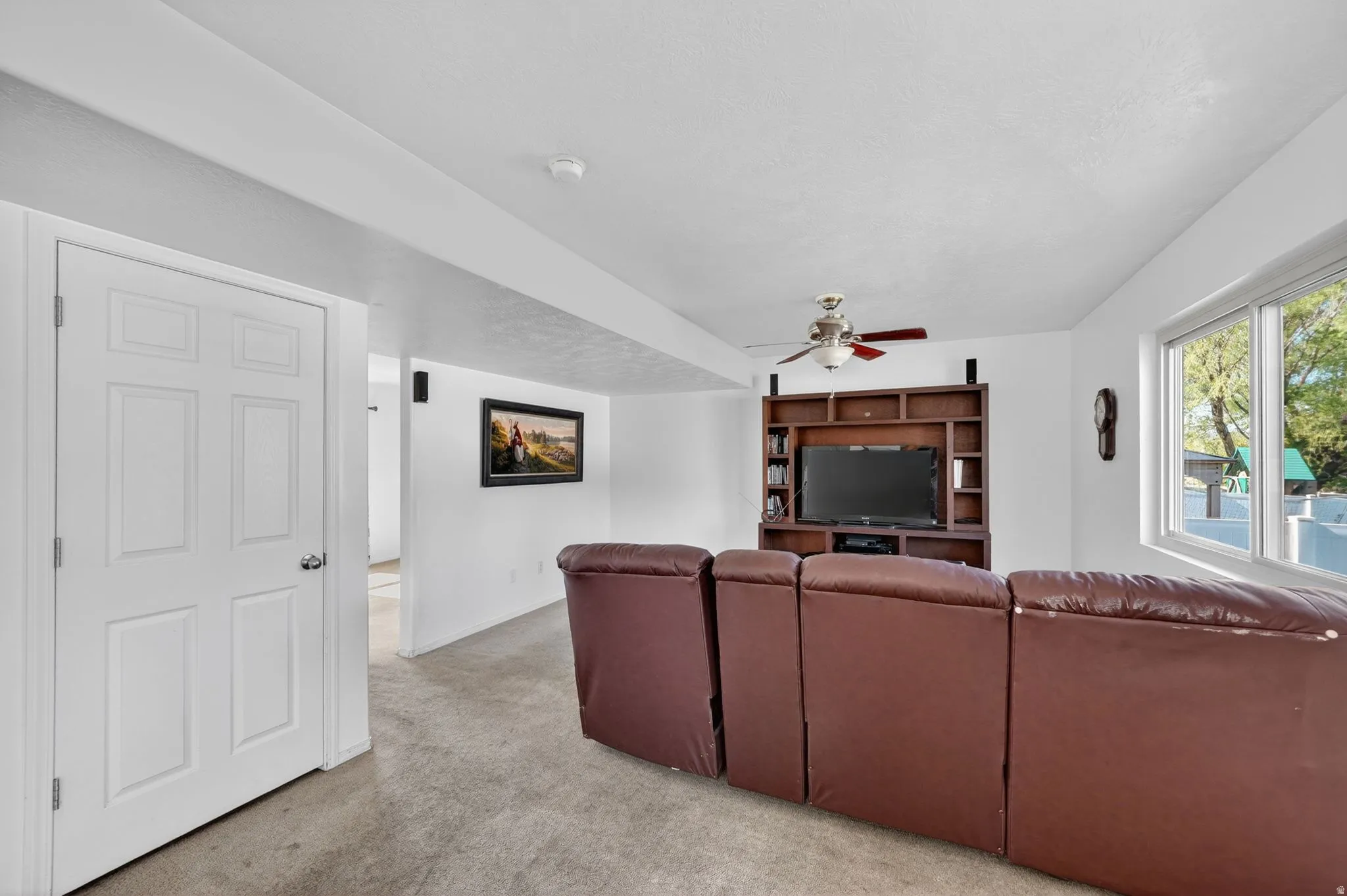 Living area featuring light colored carpet and ceiling fan